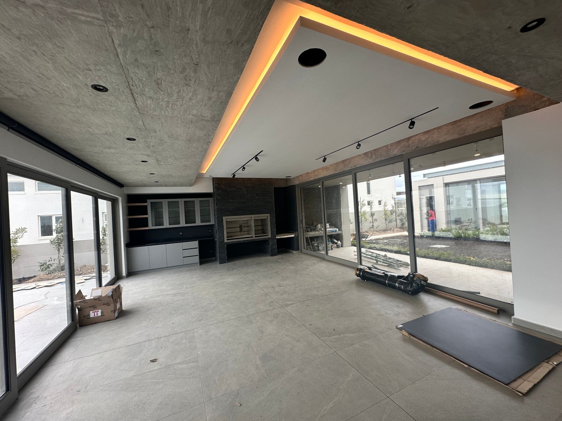 Modern interior space with large windows, concrete ceiling, built-in cabinetry, and garden view outside.